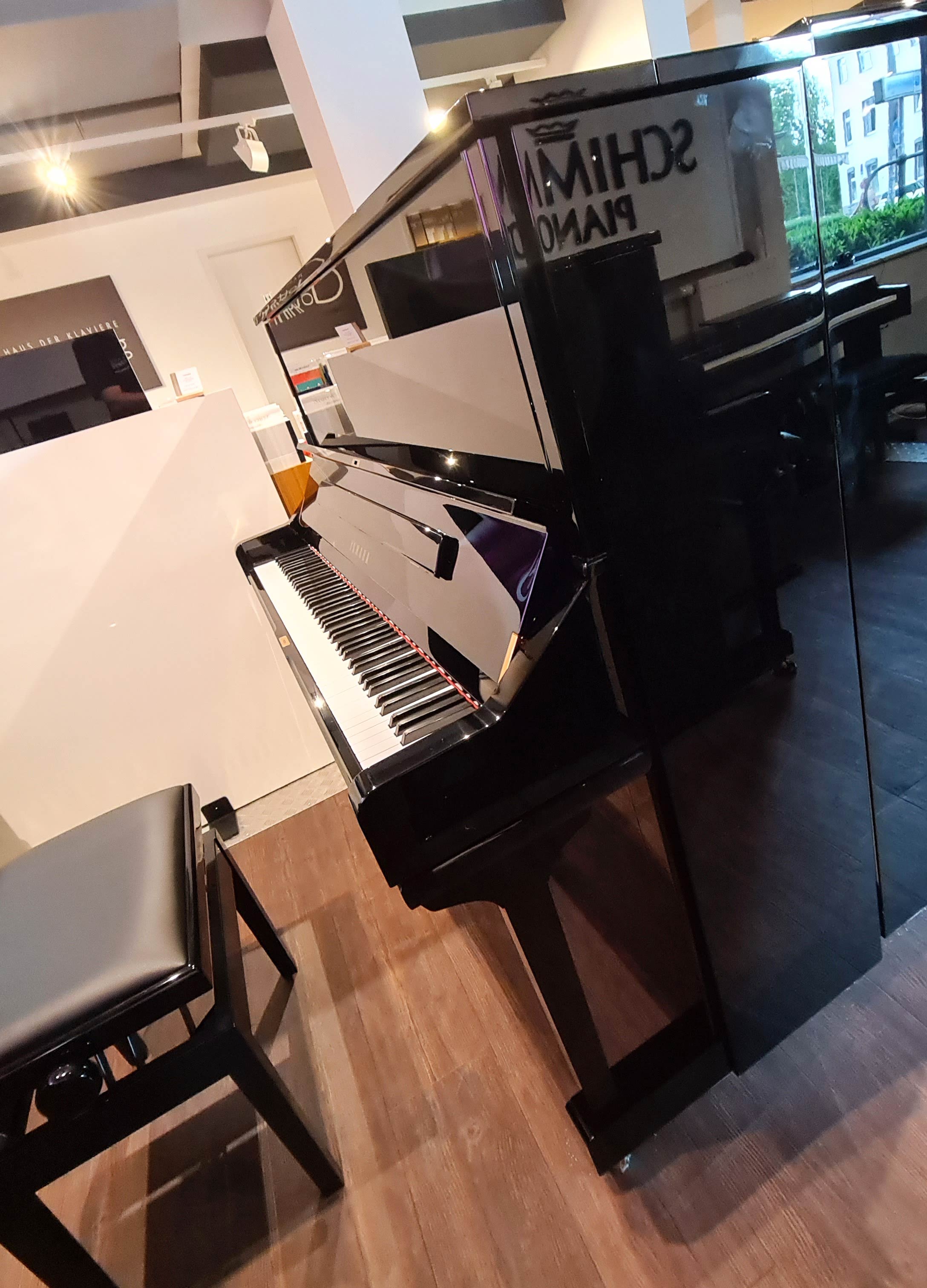 Schwarzes Klavier mit Hocker in einem hellen Musikgeschäft mit Holzfußboden und großen Fenstern​​​​​​​​​​​​​​​​​​​​​​​​​​​​​​​​​​​​​​​​​​​​​​​​​​