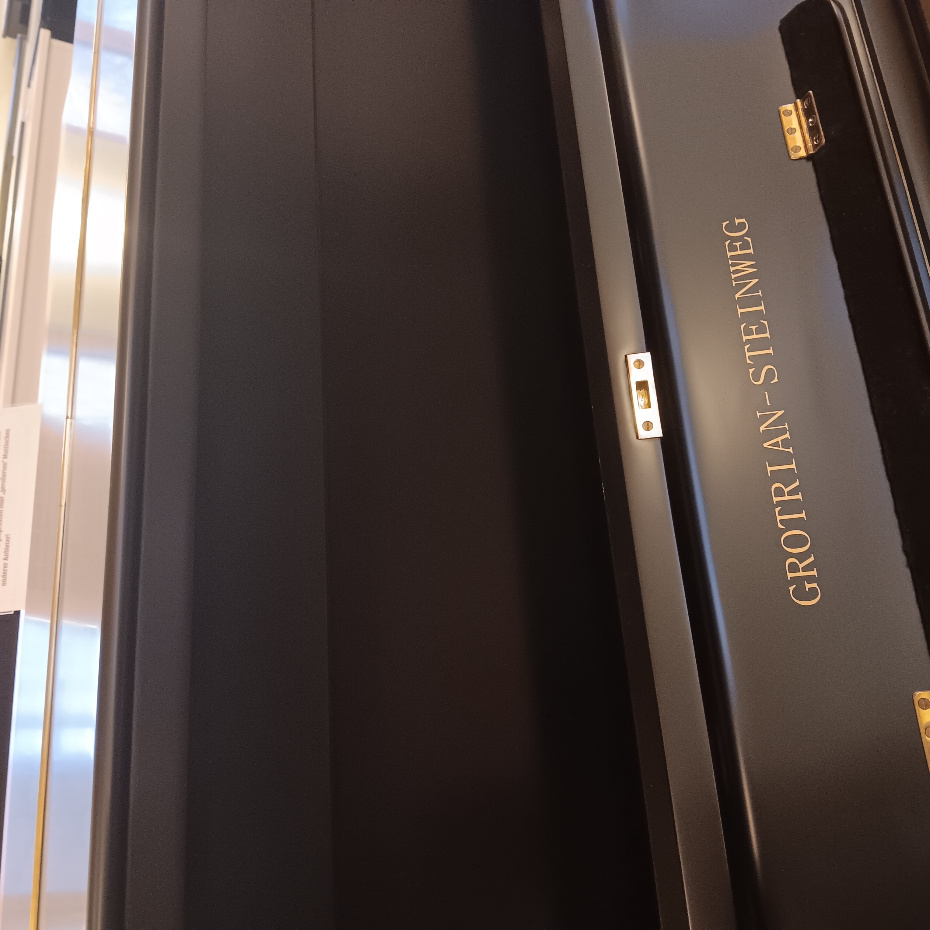 Goldener Schriftzug „Grotrian-Steinweg“ auf schwarzem Klaviergehäuse, Detailaufnahme.