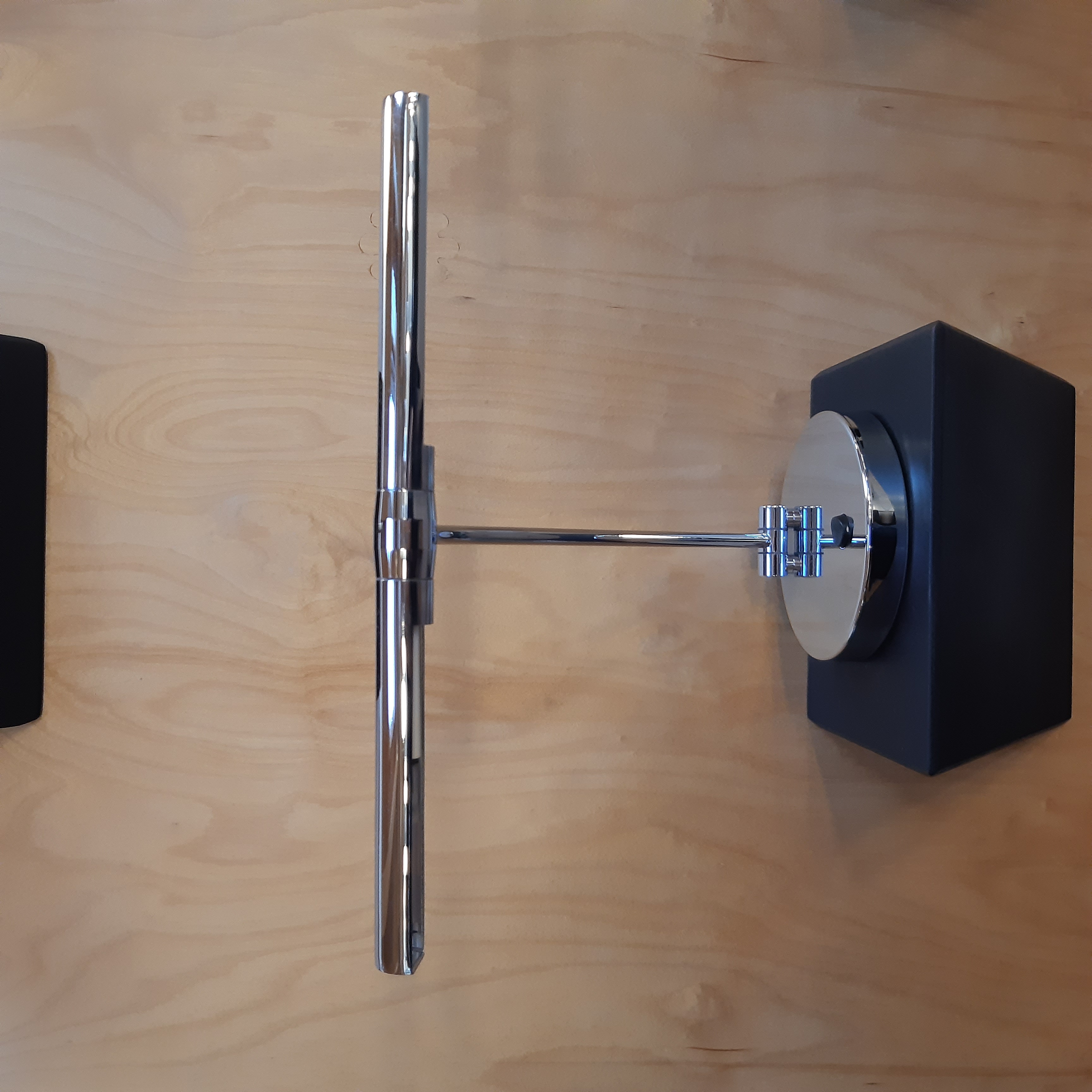 Chromfarbene Halogenleuchte Schmidt mit rundem Sockel auf schwarzem Podest vor Holzpaneel​​​​​​​​​​​​​​​​​​​​​​​​​​​​​​​​​​​​​​​​​​​​​​​​​​​​​​​​