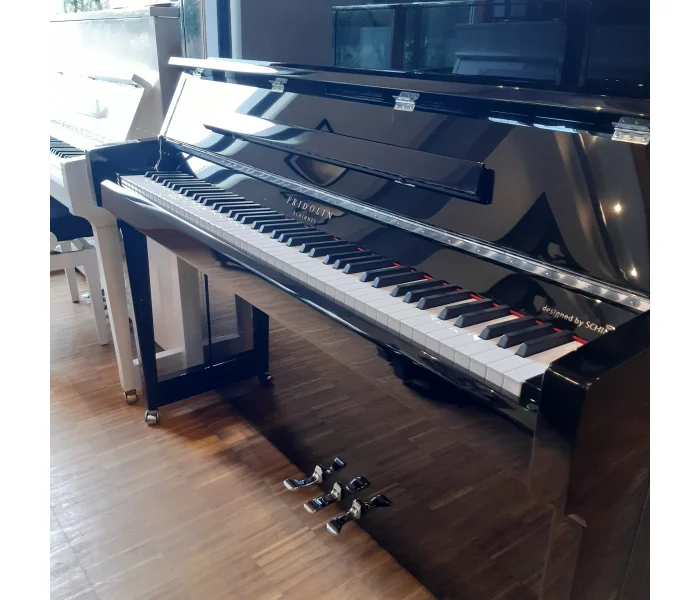 Schwarzes Fridolin Schimmel Klavier mit weißen und schwarzen Tasten steht auf Holzboden in hellem Raum mit Fensterlicht​​​​​​​​​​​​​​​​​​​​​​​​​​