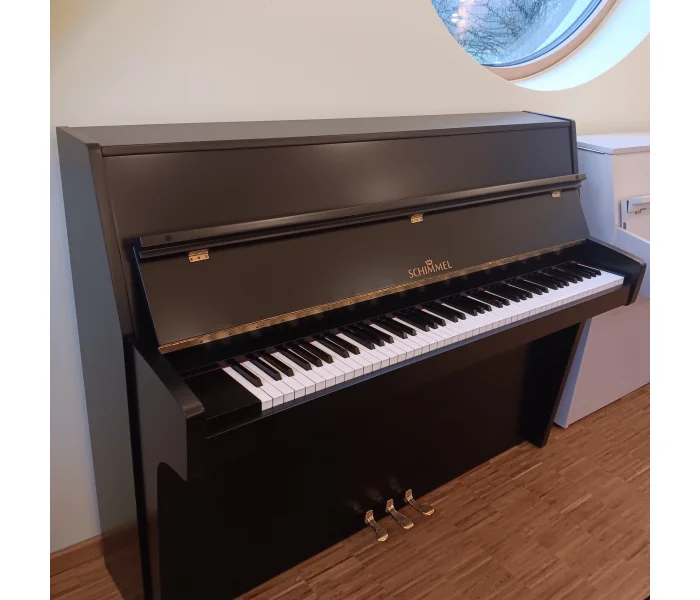 Schwarzes Schimmel-Klavier Modell 112 mit sichtbarer Klaviatur und Pedalen, schräg fotografiert.