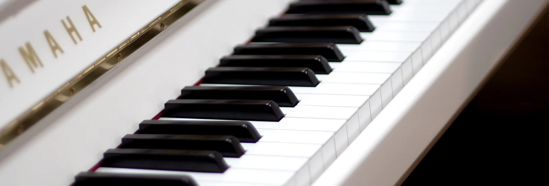 Nahaufnahme eines weißen Yamaha Klaviers mit schwarzen und weißen Tasten in heller Umgebung für Klavier Mietkauf​​​​​​​​​​​​​​​​​​​​​​​​​​​​​​​​​