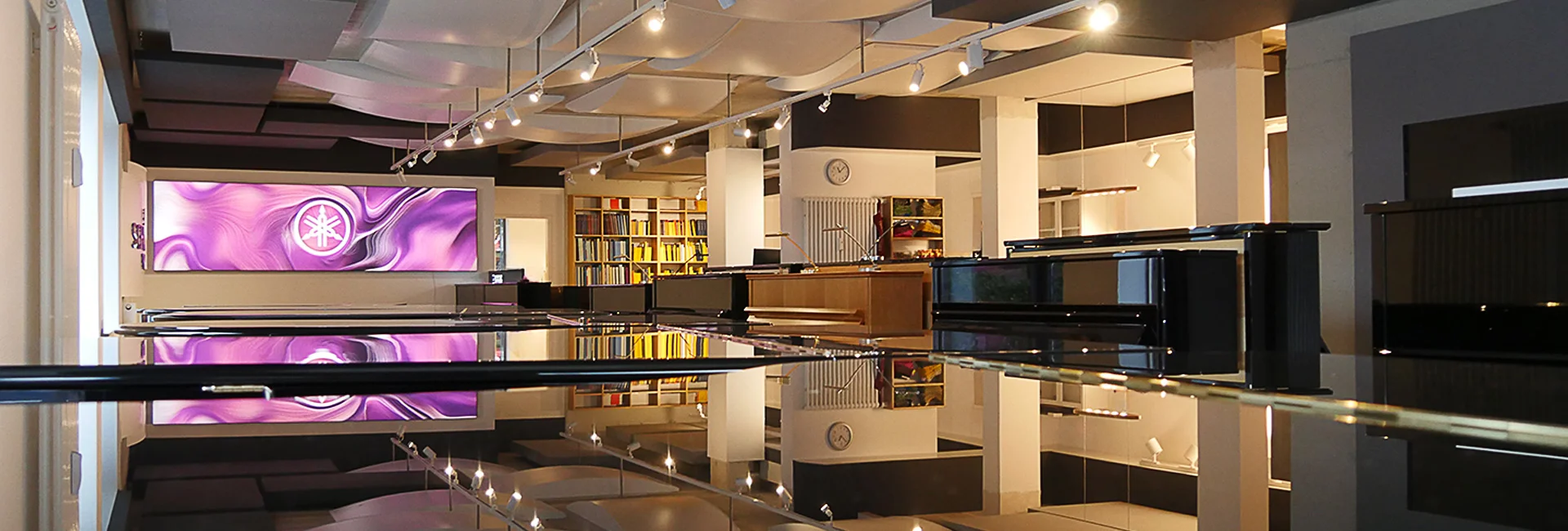 Moderne Innenansicht eines Musikhauses in Münster mit schwarzen Klavieren, Bücherregalen und heller Beleuchtung​​​​​​​​​​​​​​​​​​​​​​​​​​​​​​​​​​